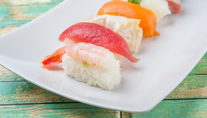 Various Japanese sushi type in white plate over wooden background