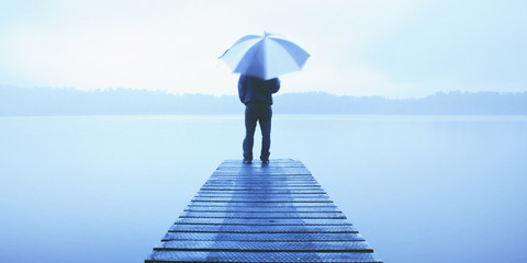 Sticker - Man Holding an Umbrella on a Jetty by Tranquil Lake Concept