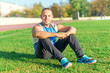 © naataali - Sporting an attractive man sitting on  grass and rests in the stadium.