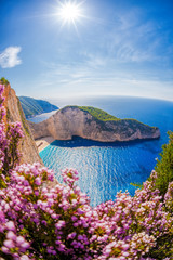 Wall Mural - Navagio beach with shipwreck and flowers against sunset, Zakynthos island, Greece