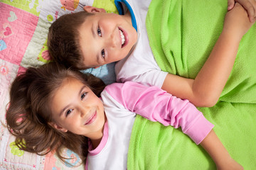 Brother and sister lying on the bed together