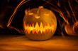Spooky Halloween pumpkin in fire with dark on the wood table