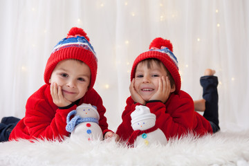 Sweet children, brother boys, playing with handmade snowmen at h