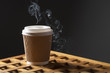 Diisposable coffee cup with smoke over dark background