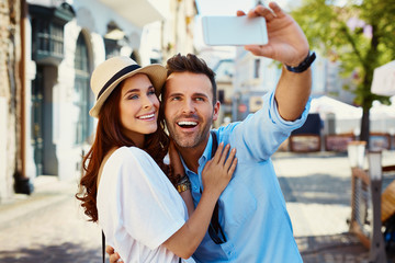 Wall Mural - Happy couple taking selfie on the city street