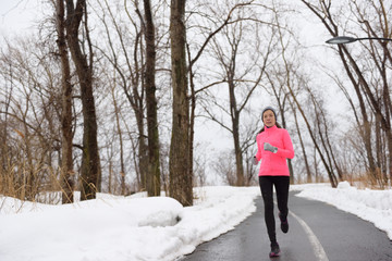 Wall Mural - Woman running in snowy city park - winter fitness