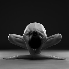 Nude yoga. Beautiful sexy body of young woman on black background