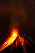 A powerful eruption from the volcano sends dark clouds of magma into the sky, glowing with intense heat and energy.
