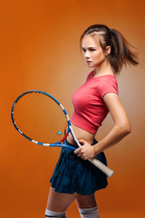 Portrait of a smiling female tennis player standing isolated on a color background