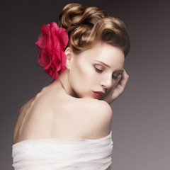 Portrait of beautiful girl with closed eyes and a red flower in her hair