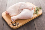 Fototapeta Góry - Raw chicken leg on cutting board on wood table