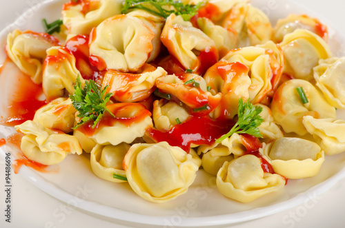 Naklejka na meble Ravioli pasta with tomato sauce and fresh parsley.