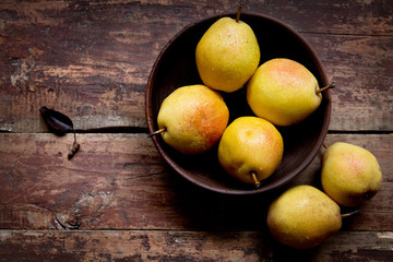 Ripe pears in a bowl on the wooden table