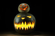 Two pumpkins on Halloween together spooky under funny on black background on table with lights

