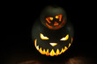 Two spooky and funny pumpkins for Halloween on empty black background isolated in dark
