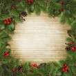 Christmas tree branches and holly on wooden board