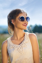 Beautiful young girl in summer wheat field on a background of bl