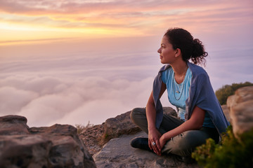woman looking out at the morning clouds from a mountain top