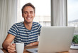 © marvent - Young man smiling with coffee at his desk