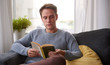 © marvent - Serious young guy reading a book on his couch at home