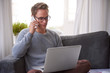 © marvent - Guy at home looking at his laptop and talking on the phone