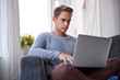 © marvent - Young man typing on his laptop on the couch