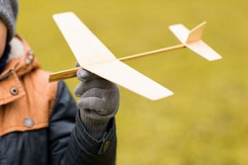 close up of little boy holding toy plane outdoors