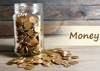 Poster - Glass jar with coins on wooden background