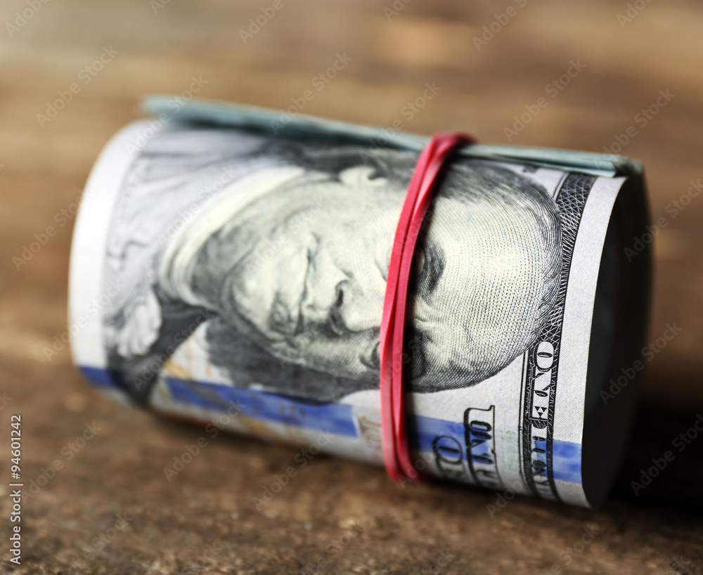 Dollars roll on wooden background