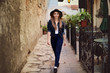 Portrait of young beautiful woman wearing hat walking in the old city. Street fashion concept. Toned 