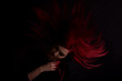 Dark portrait of a beautiful girl with developing long red hair and fingers in blood