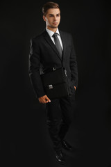 Poster - Elegant man in suit with briefcase on dark background