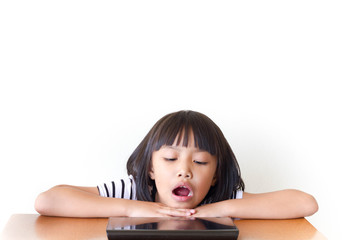 Little girl with bored tablet pc sitting on the wooden table - Technology and children concept