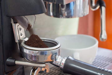 coffee grinder grinding freshly roasted coffee beans into a coff