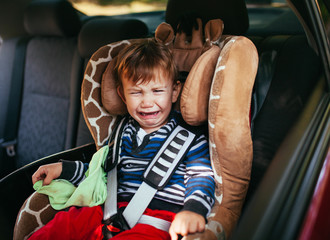 Crying baby boy in car seat.