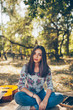 © kegfire - beautiful teenage girl wearing casual clothes sitting outdoors in forest. Cute hipster brunette young woman with guitar on autumn day
