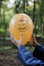 Two Hands Holding An Halloween Ballon In The Forrest