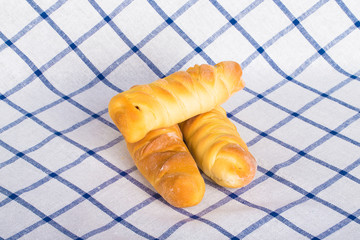 Fresh baked sausages buns on checkered tablecloth like backgroun