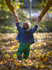 kleinkind mit eltern beim spaziergang im herbst