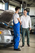 © luckybusiness - smiling auto mechanic and client shaking hands