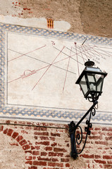 Wall Mural - view of a middle ages sundial painted over a wall, with an old-fashioned street light