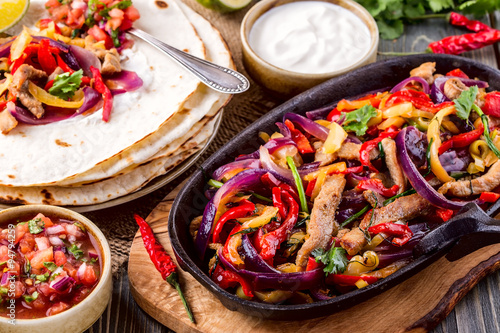 Fotografía Fajitas de cerdo con cebolla y pimienta de colores, servido con tortill