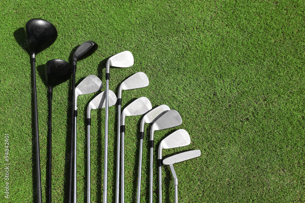 Different golf clubs in a row on a green grass