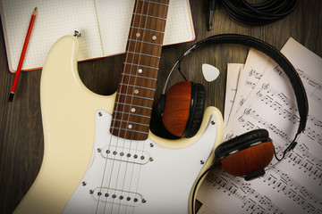 Wall Mural - Electric guitar with headphones, musical notes and note book on wooden background