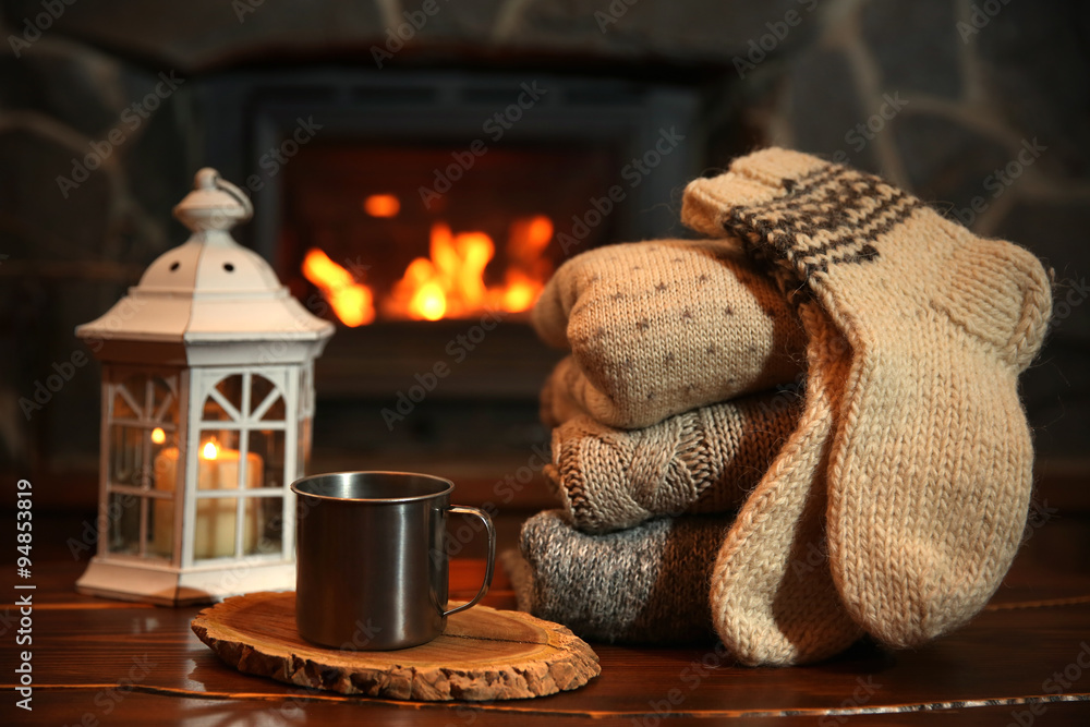 Knitted clothes on table on fireplace background