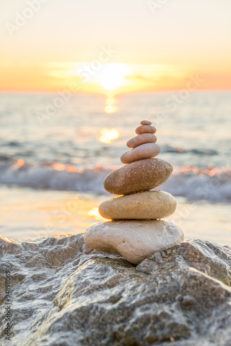 Fototapeta na wymiar Stones pyramid on sand symbolizing zen, harmony, balance. Ocean