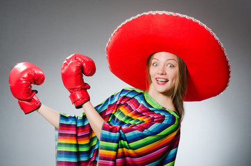 Girl in mexican vivid poncho and box gloves against gray