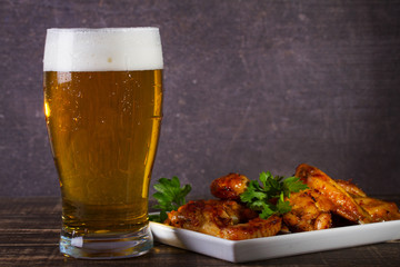 Wall Mural - Glass of beer and chicken wings on dark wooden background