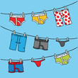 A set of a variety of colorful, cartoon underwear hang to dry on an outdoor clothesline. 