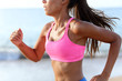 © Maridav - Midsection of determined woman jogging on beach. Young female is wearing sports bra and shorts. Sporty runner is exercising on sunny day.